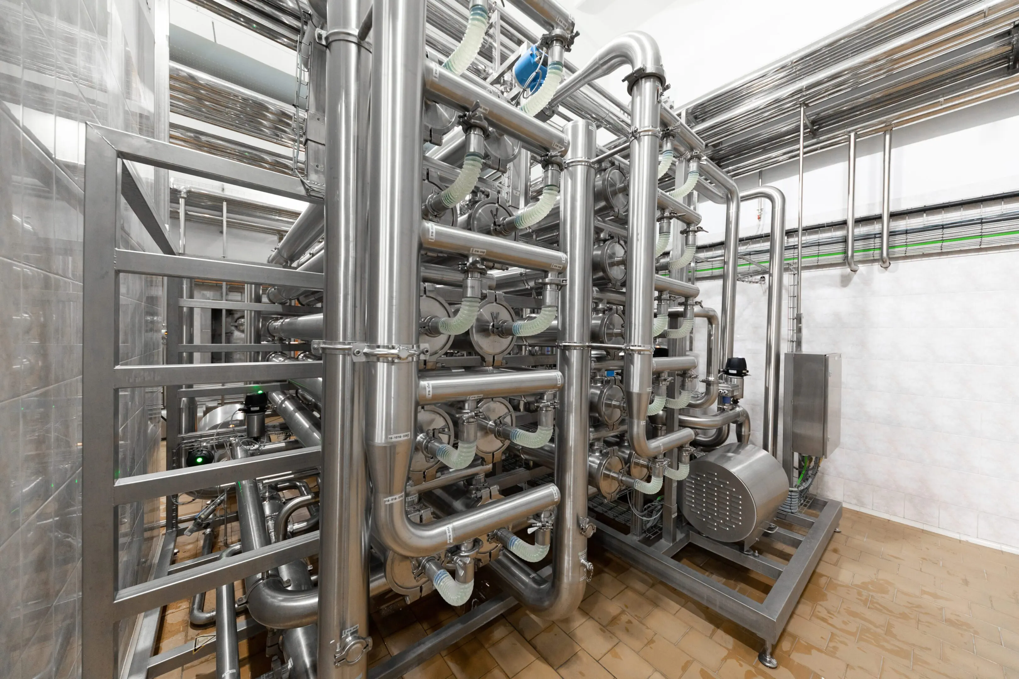 Complex network of stainless steel pipes in an industrial facility.