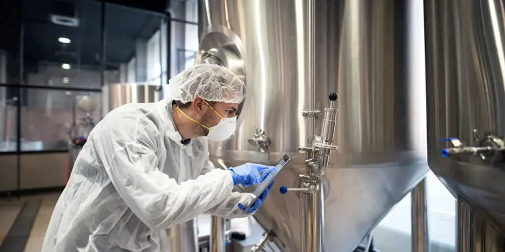 Technician inspecting large stainless steel tank.