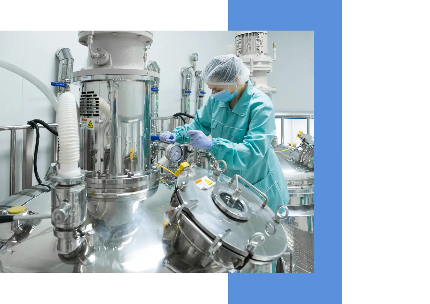 Scientist in protective gear working with stainless steel equipment in a lab.