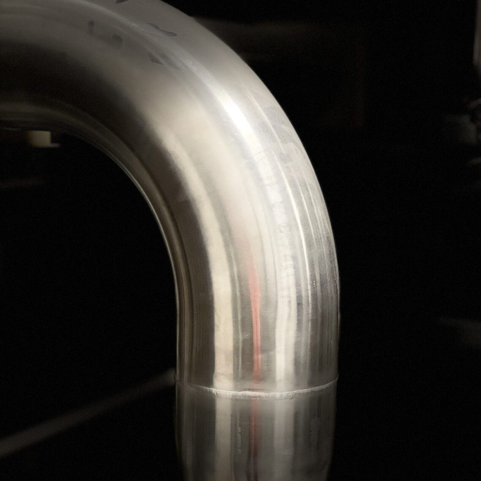 Close-up of a curved metal pipe with reflective surface.